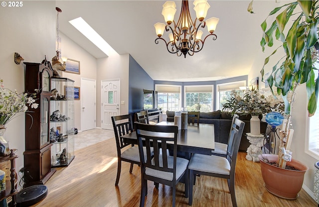 dining room featuring vaulted ceiling with skylight and light hardwood / wood-style floors