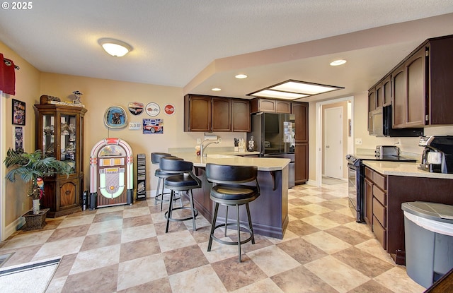 kitchen with electric range oven, a textured ceiling, a kitchen bar, black refrigerator, and kitchen peninsula