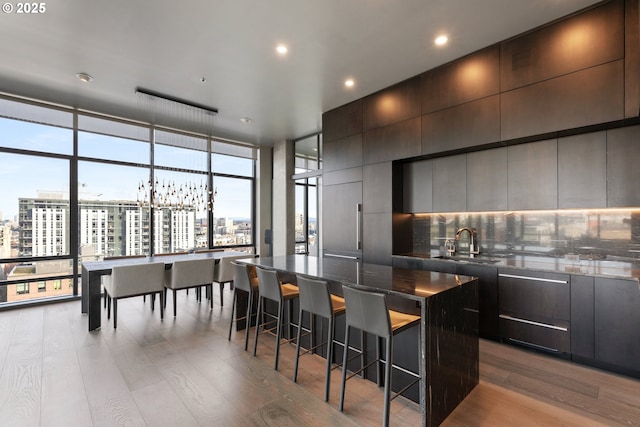 kitchen with sink, a breakfast bar area, wood-type flooring, and a spacious island