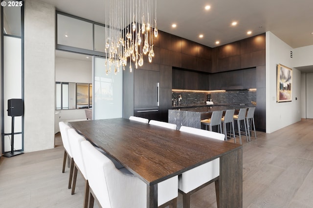 dining room with a towering ceiling and light wood-type flooring