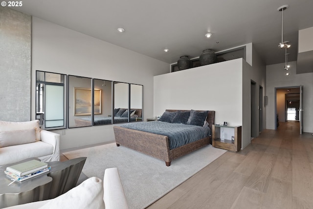 bedroom featuring a towering ceiling and light hardwood / wood-style floors