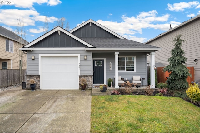 view of front of house with covered porch, a garage, and a front yard