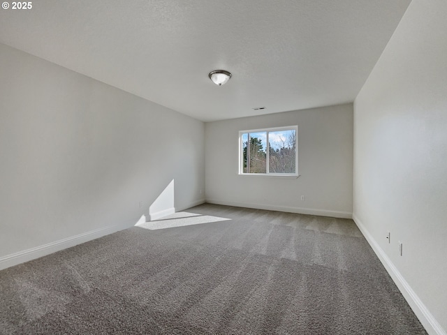 spare room featuring carpet floors and baseboards