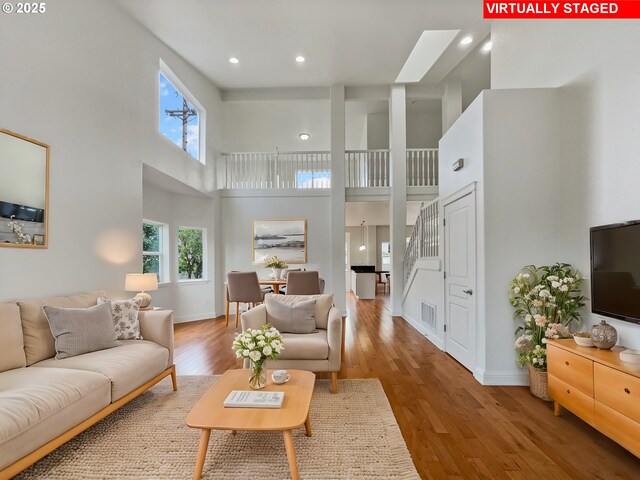 unfurnished living room with a healthy amount of sunlight, hardwood / wood-style flooring, baseboards, and high vaulted ceiling