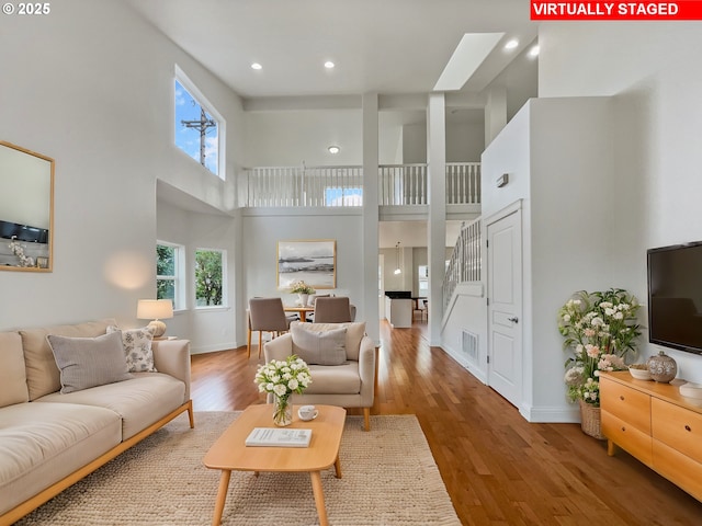 living area featuring plenty of natural light, a towering ceiling, and wood finished floors