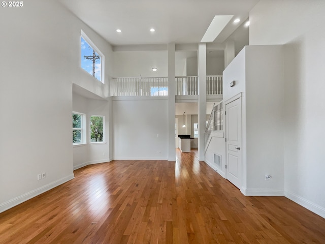 unfurnished living room with baseboards, a high ceiling, and hardwood / wood-style floors