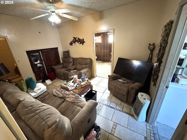 living area featuring a textured ceiling, light tile patterned floors, and a ceiling fan