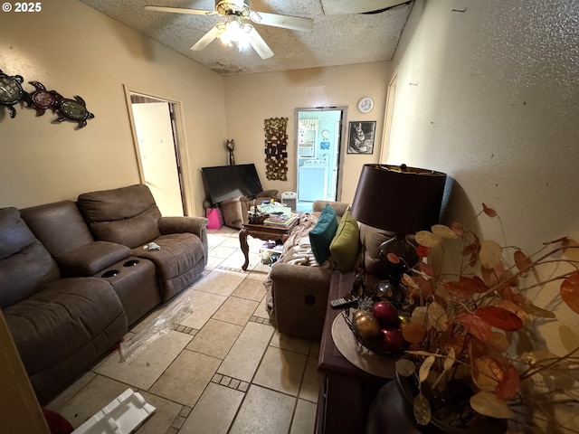 living room with a ceiling fan, light tile patterned flooring, and a textured ceiling