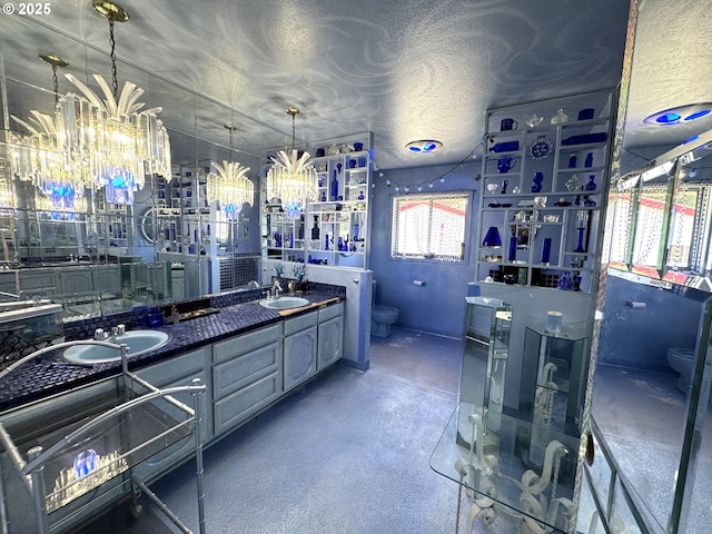 bathroom with toilet, a textured ceiling, double vanity, and a sink