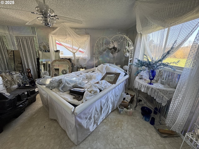 bedroom featuring ceiling fan, a textured ceiling, and wallpapered walls