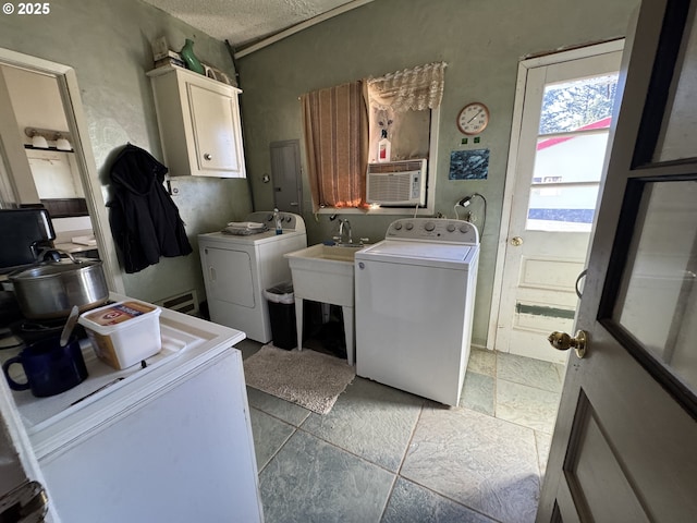 laundry area with washer and clothes dryer, stone tile floors, cabinet space, a sink, and a textured ceiling