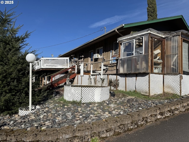 view of side of home with stairs, a wooden deck, and a sunroom