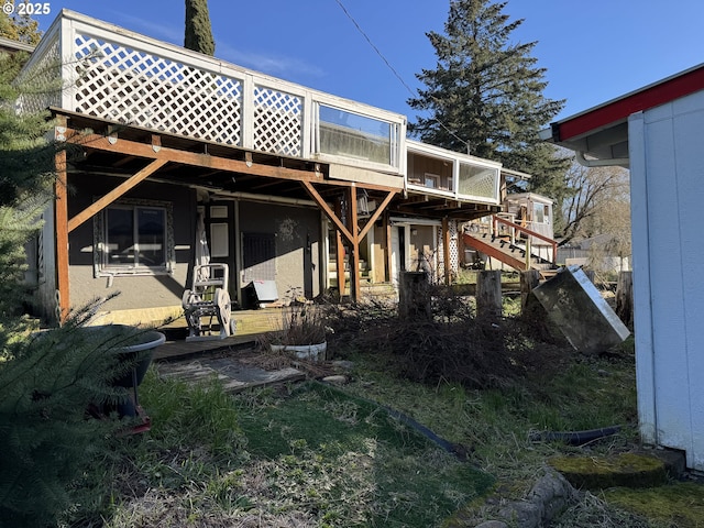 rear view of property with stairway and a deck