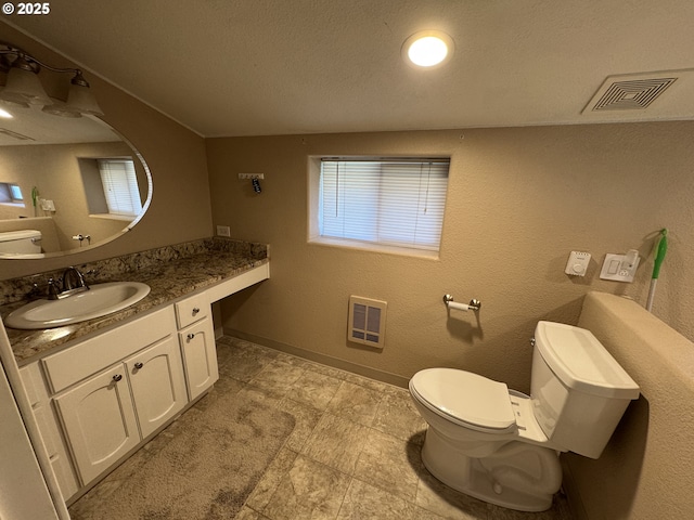 bathroom featuring toilet, vanity, visible vents, baseboards, and heating unit