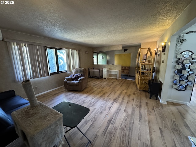 living area with a textured ceiling, baseboards, and wood finished floors