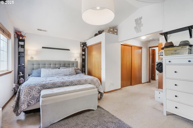 bedroom with visible vents, light colored carpet, baseboards, lofted ceiling, and multiple closets