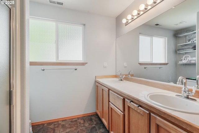 bathroom featuring a sink, baseboards, double vanity, and visible vents