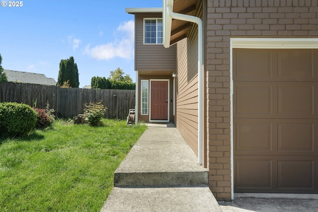 property entrance featuring a lawn, brick siding, fence, and a garage