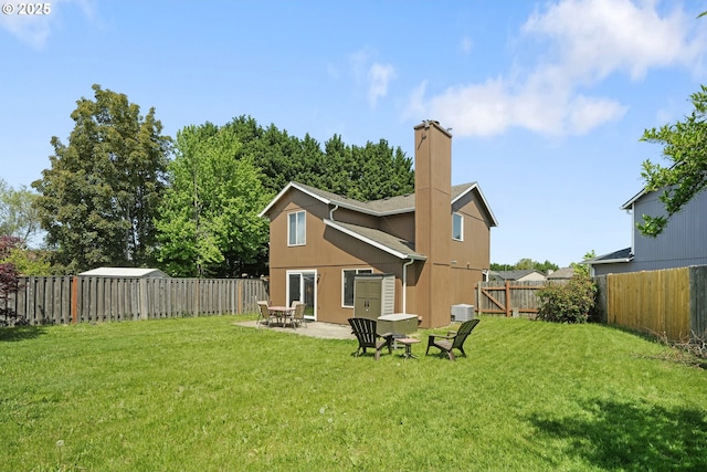 rear view of house featuring a lawn, a fenced backyard, a chimney, and a patio