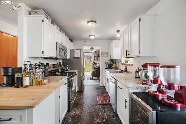 kitchen featuring a ceiling fan, a sink, light countertops, stainless steel appliances, and white cabinetry