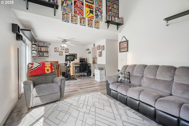 living room featuring a ceiling fan, a towering ceiling, and wood finished floors