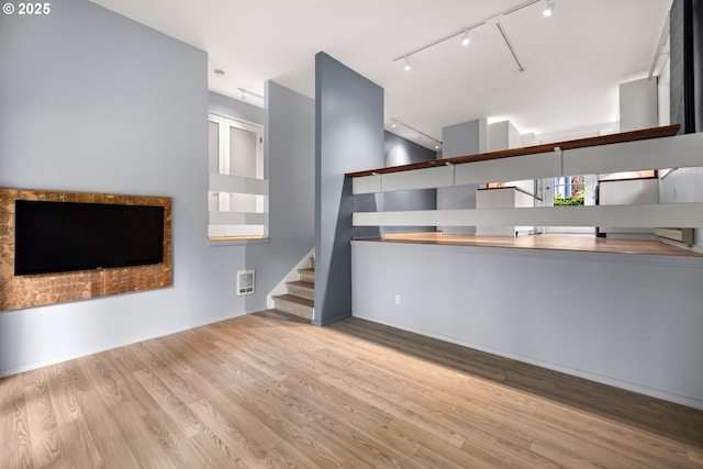4360 SW Dickinson St Unit 35, Portland, OR 97219 - unfurnished living room with track lighting, wood finished floors, and stairway