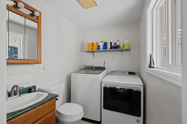 clothes washing area with a wealth of natural light, laundry area, a sink, and washer and clothes dryer