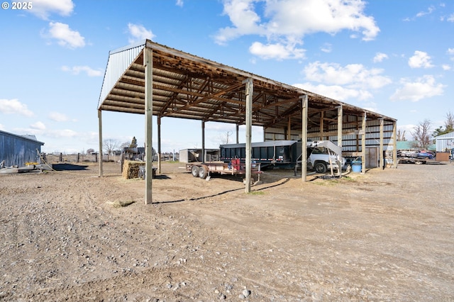 view of car parking with a detached carport, driveway, and an outbuilding