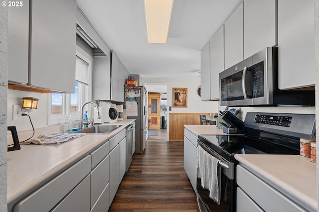 kitchen with stainless steel appliances, dark wood-type flooring, a sink, and light countertops