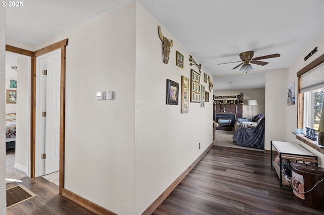 hall with visible vents, dark wood finished floors, and baseboards