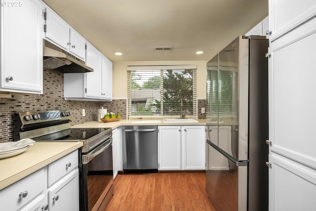 1771 NW 143rd Ave Unit 38, Portland, OR 97229 - kitchen featuring stainless steel appliances, under cabinet range hood, light wood-style floors, white cabinetry, and backsplash