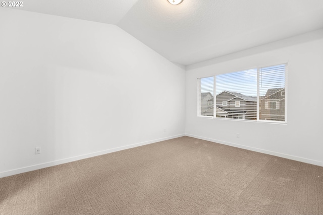 carpeted empty room featuring vaulted ceiling