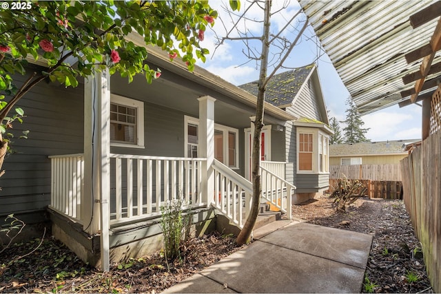 doorway to property featuring covered porch and fence