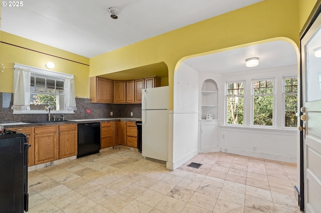 kitchen with brown cabinetry, a healthy amount of sunlight, black appliances, and a sink