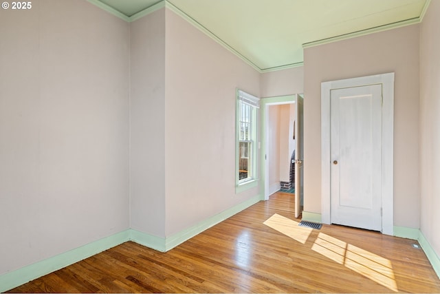 unfurnished room with visible vents, baseboards, crown molding, and light wood-style floors