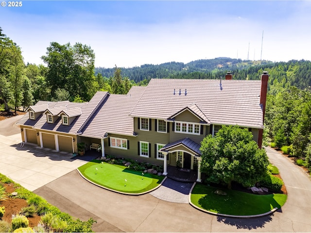 2030 W 34th Ave, Eugene, OR 97405 - view of front facade featuring an area to practice putting, driveway, a wooded view, and a chimney