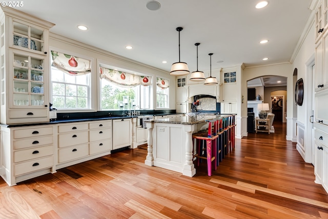 2030 W 34th Ave, Eugene, OR 97405 - kitchen with arched walkways, ornamental molding, a center island, light wood-style flooring, and glass insert cabinets