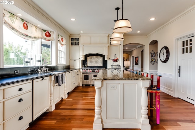 2030 W 34th Ave, Eugene, OR 97405 - kitchen featuring double oven range, a kitchen island, dark wood-style floors, arched walkways, and ornamental molding