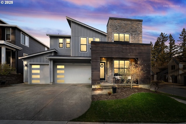 contemporary house featuring driveway, an attached garage, board and batten siding, and stone siding