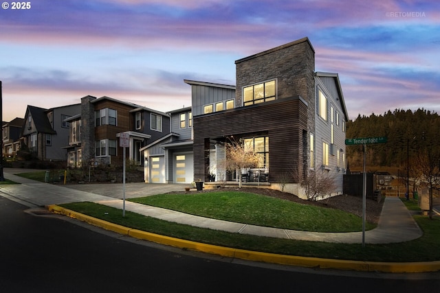 contemporary house with a front lawn, driveway, an attached garage, and board and batten siding