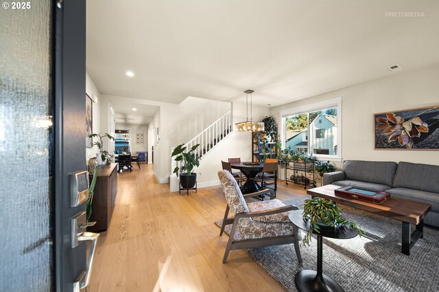 living room with an inviting chandelier and light wood-type flooring