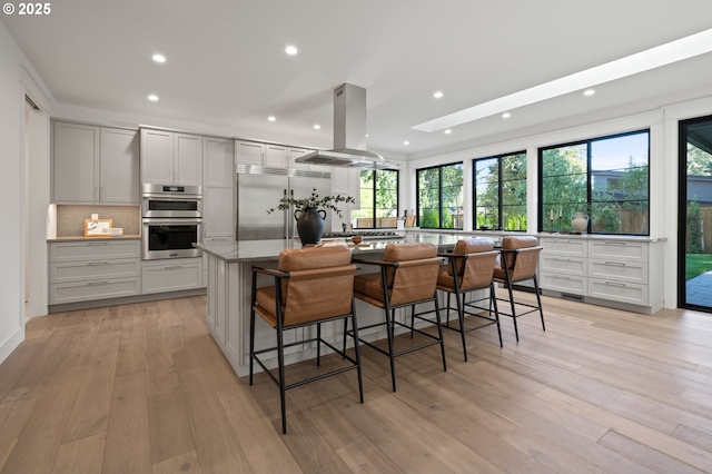 kitchen featuring stainless steel appliances, island exhaust hood, plenty of natural light, a kitchen island, and recessed lighting
