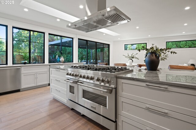 kitchen with ventilation hood, stainless steel appliances, a skylight, recessed lighting, and white cabinetry