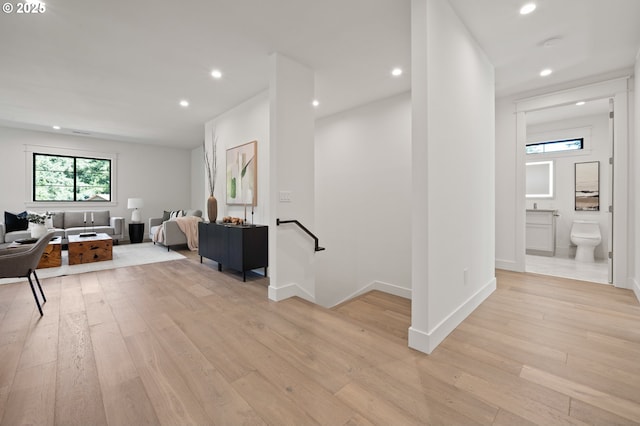 hall with an upstairs landing, light wood finished floors, and recessed lighting