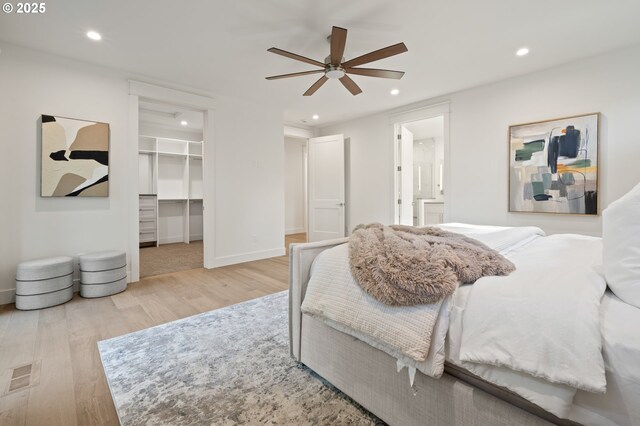 bedroom featuring wood finished floors, recessed lighting, a spacious closet, baseboards, and ensuite bathroom