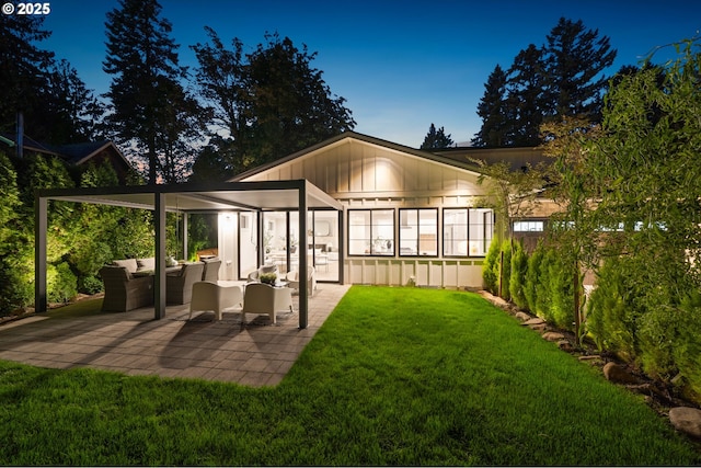 rear view of property featuring an outdoor hangout area, a patio area, a lawn, and board and batten siding