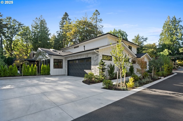 view of side of property with a garage, concrete driveway, board and batten siding, and stone siding