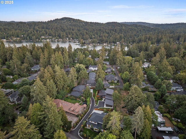 aerial view of property and surrounding area with a forest, a large body of water, and nearby suburban area