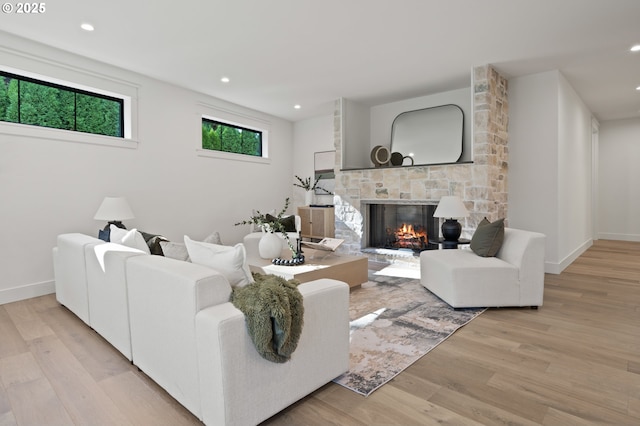 living area with a stone fireplace, light wood-type flooring, recessed lighting, and baseboards