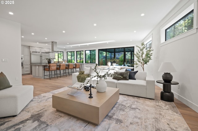 living room with healthy amount of natural light, recessed lighting, and light wood-type flooring